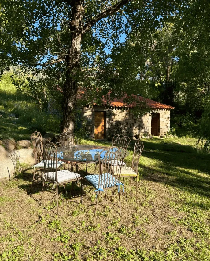 Une bâtisse en pierre du domaine et son salon de jardin, sous les arbres